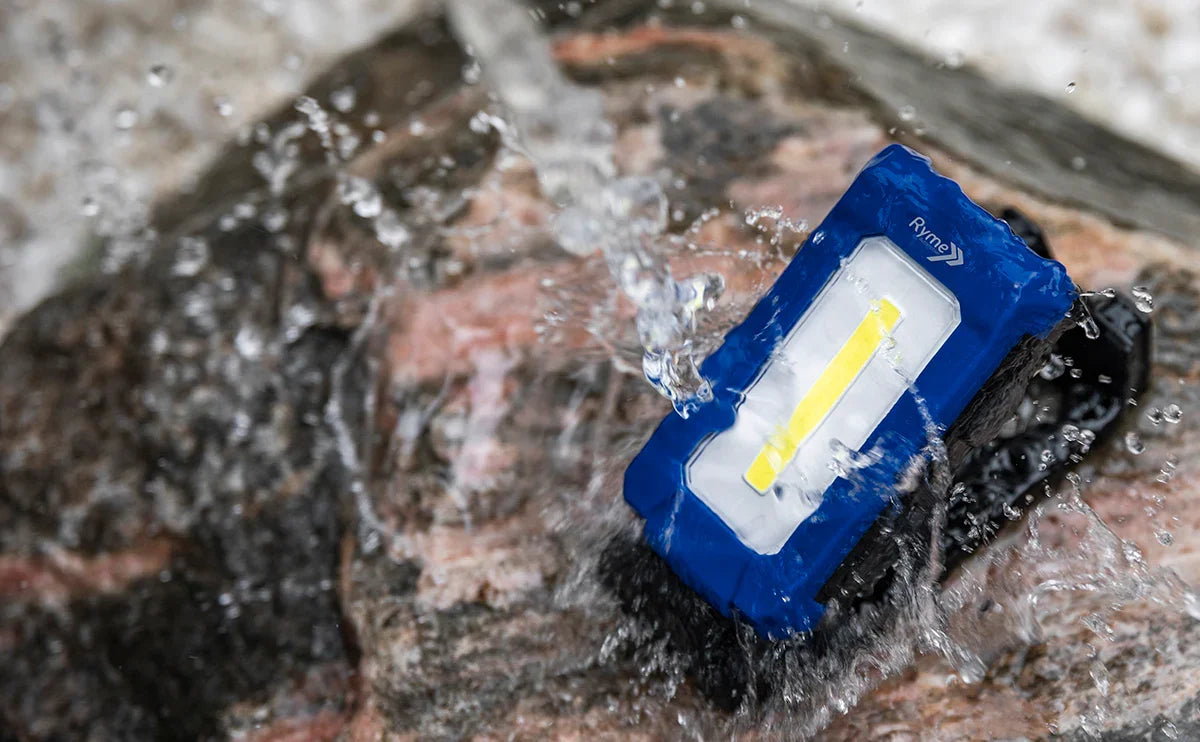 Baliza o foco de trabajo LED resistente al agua sobre roca con agua salpicando