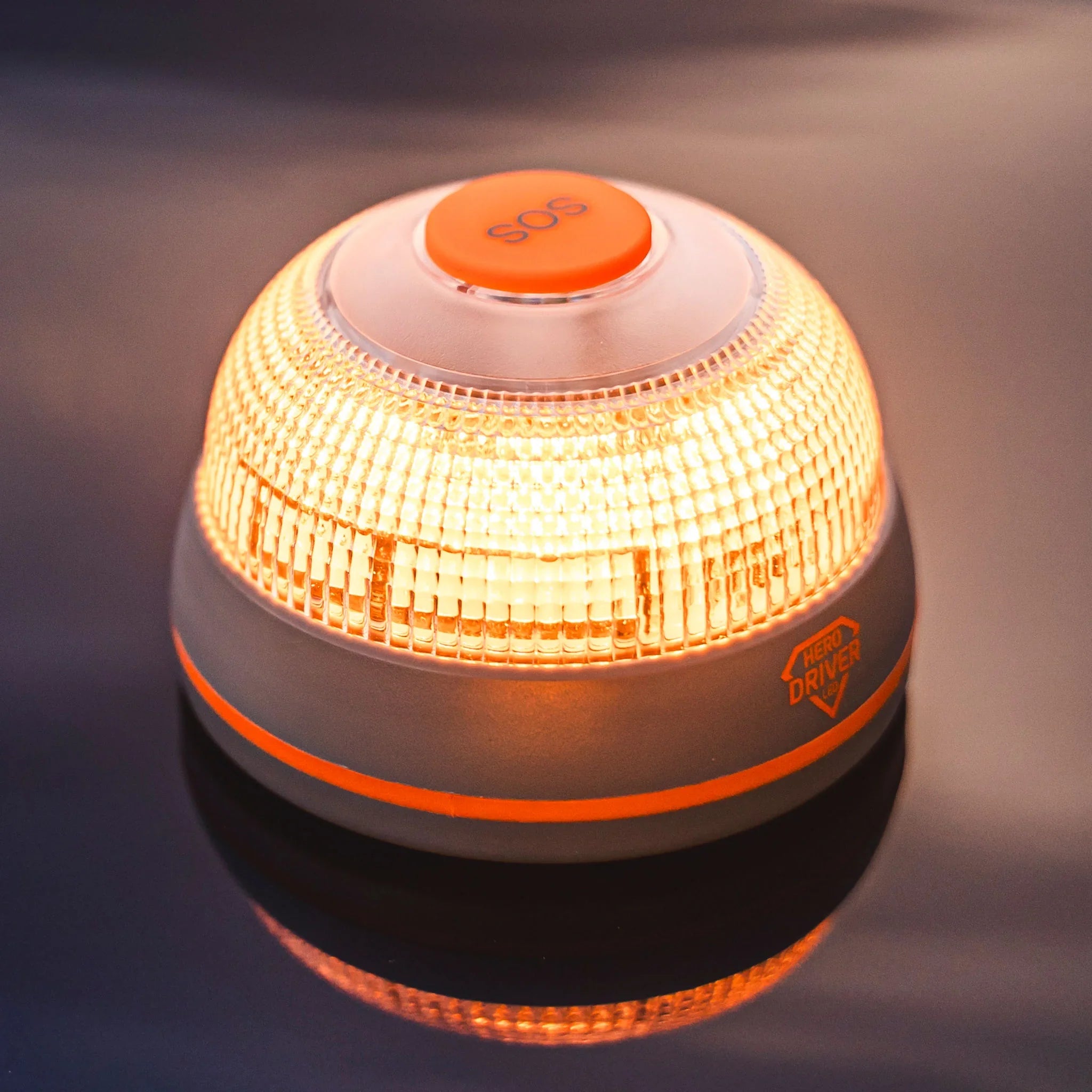 Luz de señalización LED naranja con botón SOS y logo Hero Driver sobre superficie reflejante