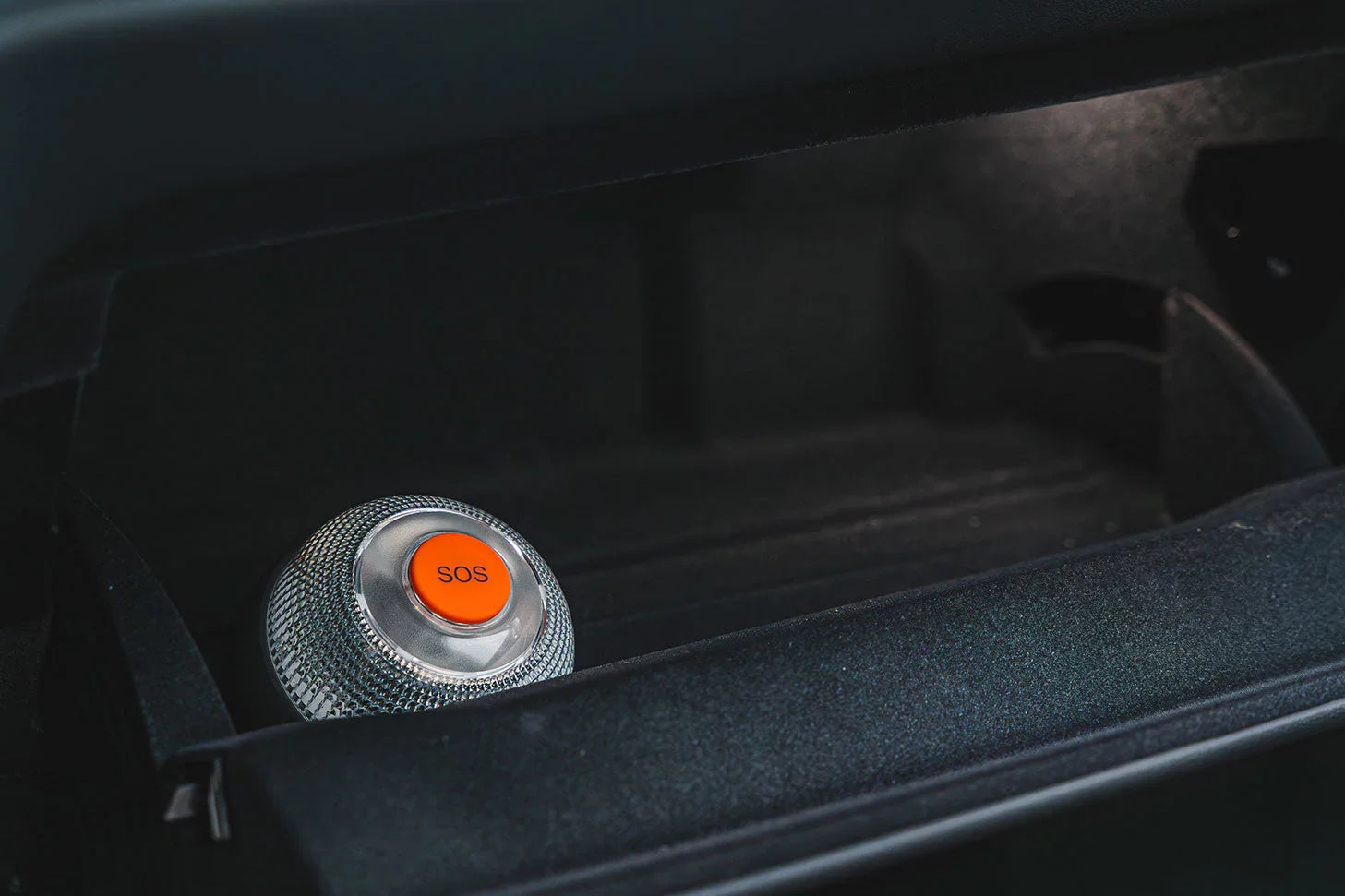 Botón SOS naranja en consola negra de vehículo para emergencias y seguridad en autos