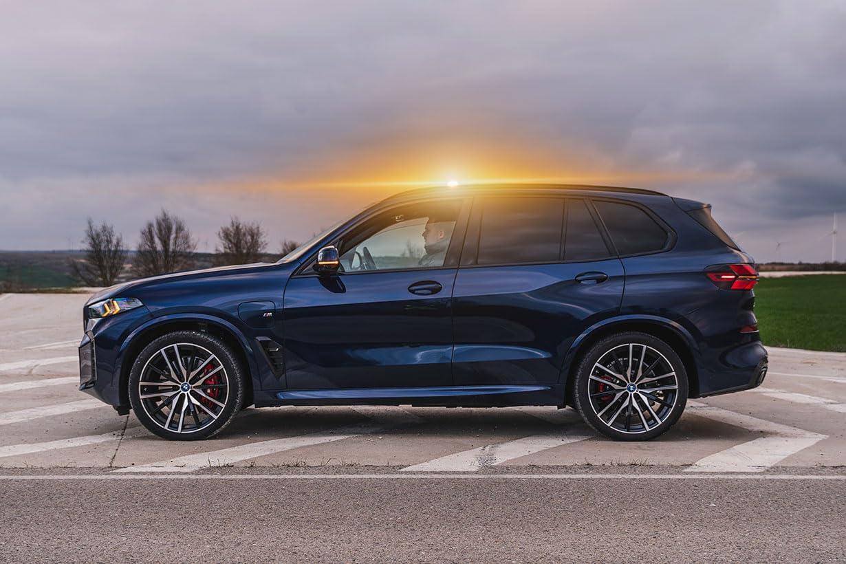 SUV azul oscuro BMW M estacionado con conductor dentro al atardecer en carretera